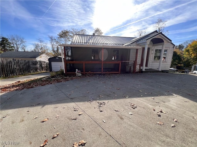 rear view of property with a sunroom, an outbuilding, and a garage