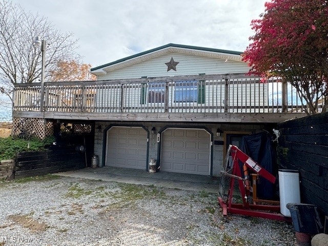 rear view of house featuring a wooden deck and a garage