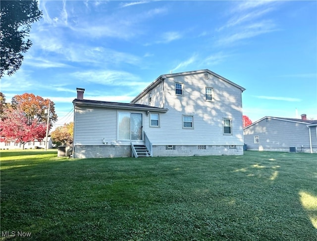 rear view of property with central air condition unit and a yard