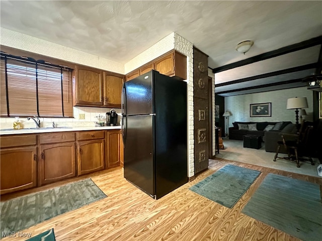 kitchen featuring light hardwood / wood-style floors, sink, and black fridge