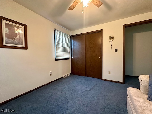 unfurnished bedroom with dark colored carpet, a closet, and ceiling fan