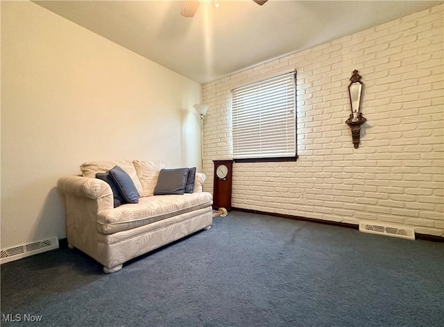 living area with ceiling fan, brick wall, and dark colored carpet