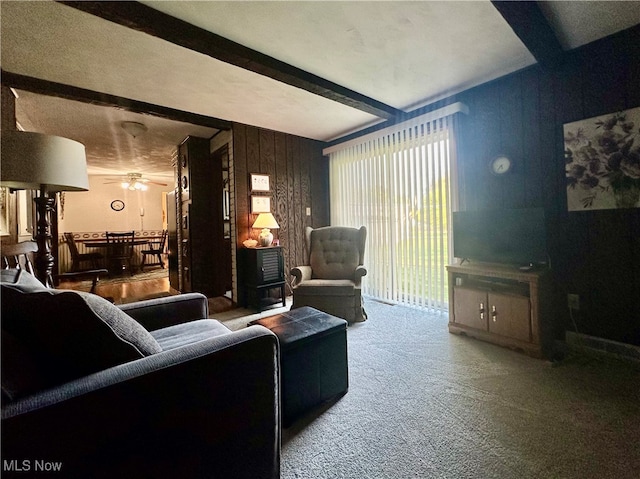 carpeted living room with ceiling fan and beamed ceiling