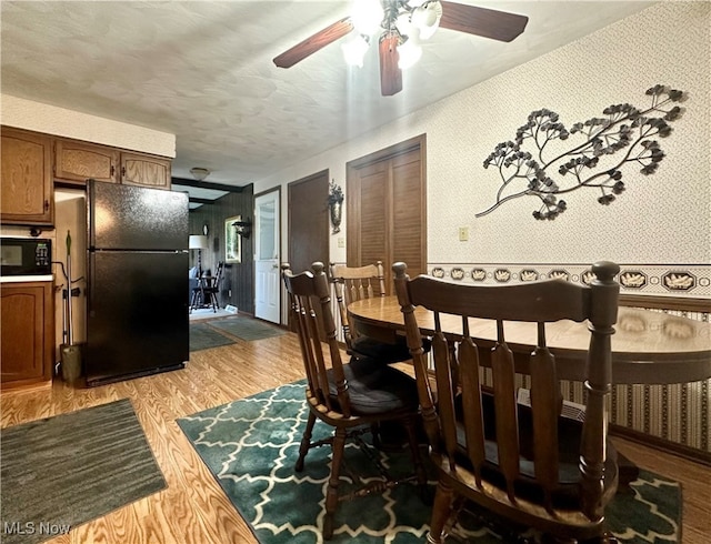 dining room featuring light hardwood / wood-style floors, a textured ceiling, and ceiling fan