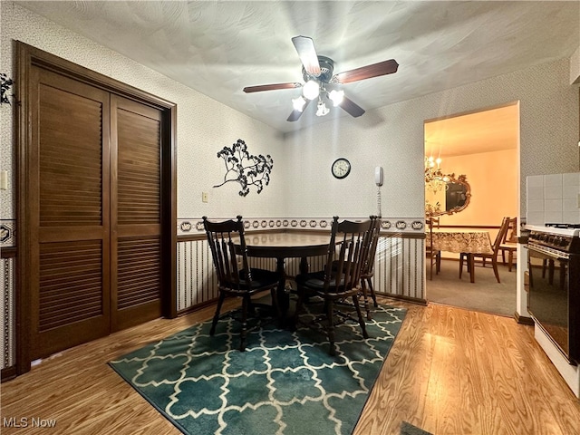 dining space featuring hardwood / wood-style flooring and ceiling fan with notable chandelier