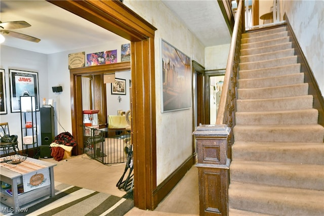 staircase featuring ceiling fan