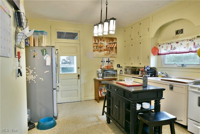 kitchen with stainless steel refrigerator, sink, pendant lighting, and white stove