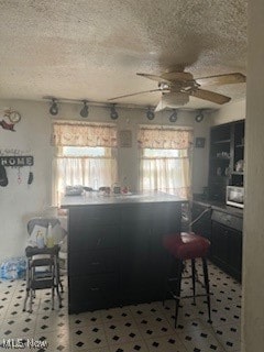 kitchen with a breakfast bar area, a textured ceiling, and ceiling fan