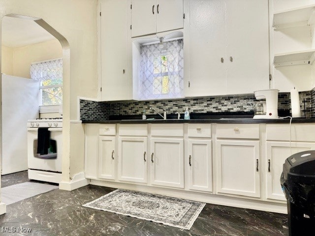 kitchen with sink, white cabinets, white stove, and tasteful backsplash