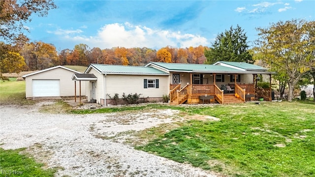 single story home featuring a front lawn, an outbuilding, a garage, and covered porch