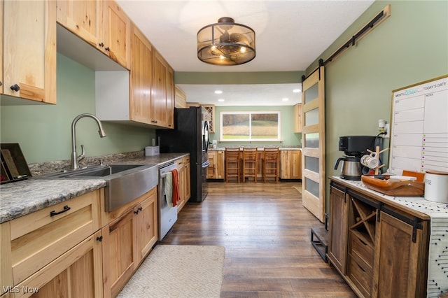 kitchen with sink, dishwasher, a barn door, dark hardwood / wood-style flooring, and light stone counters