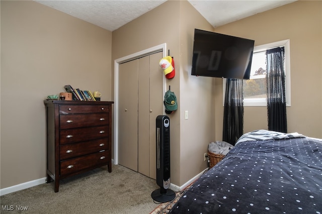 bedroom with a closet, a textured ceiling, light colored carpet, and vaulted ceiling