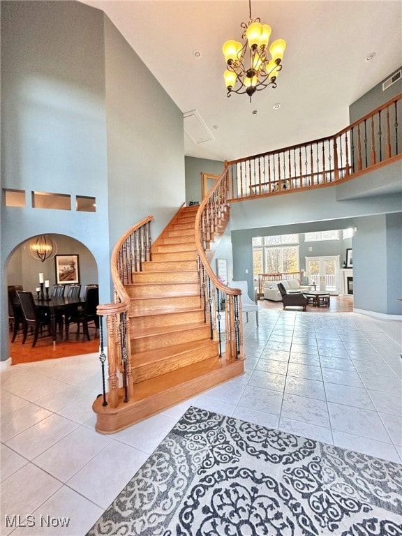 staircase featuring a notable chandelier, tile patterned floors, and a high ceiling