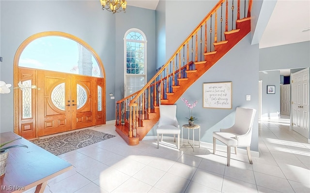 foyer featuring a towering ceiling, a chandelier, and tile patterned flooring