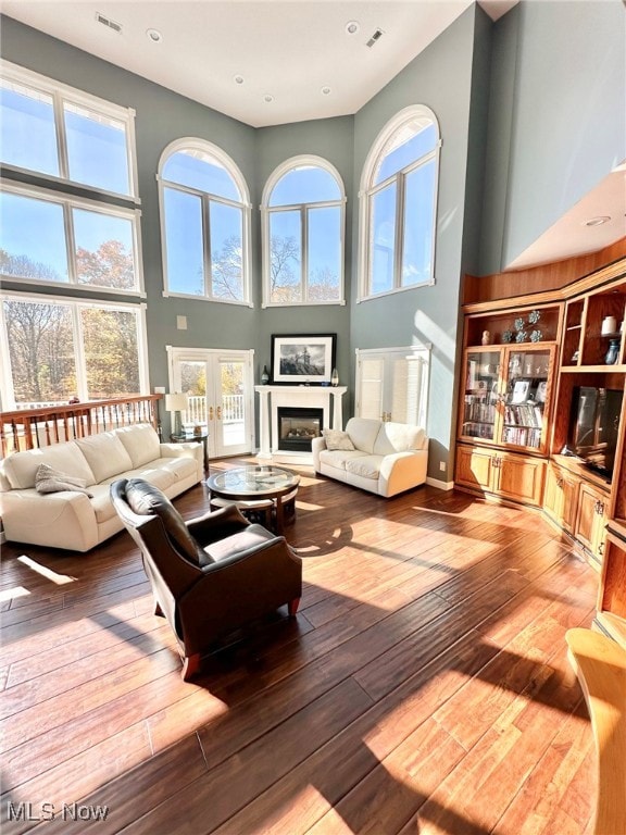 living room featuring french doors, hardwood / wood-style flooring, and a towering ceiling