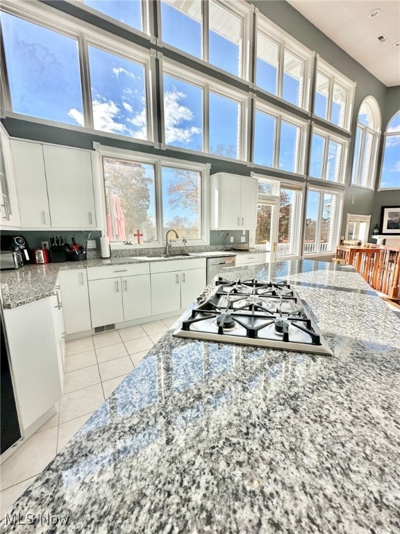 kitchen featuring a high ceiling, white cabinetry, and a healthy amount of sunlight