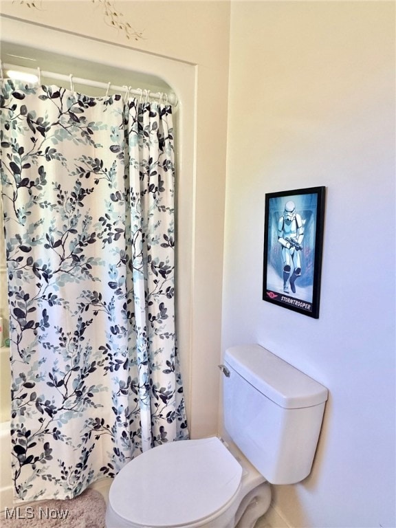 bathroom featuring a shower with shower curtain and toilet