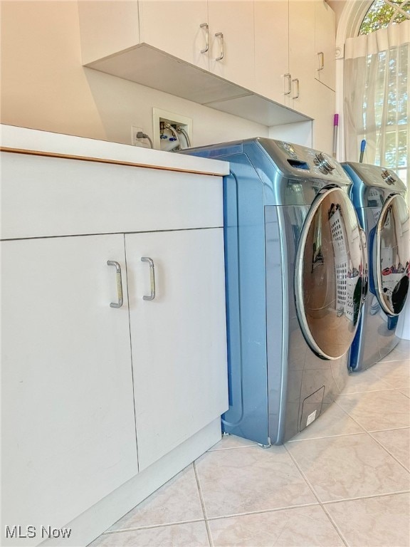 laundry room featuring light tile patterned flooring, washer and dryer, and cabinets