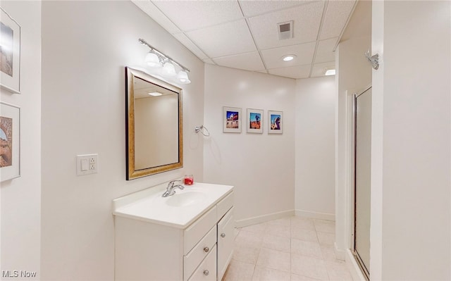 bathroom with vanity, an enclosed shower, a paneled ceiling, and tile patterned floors