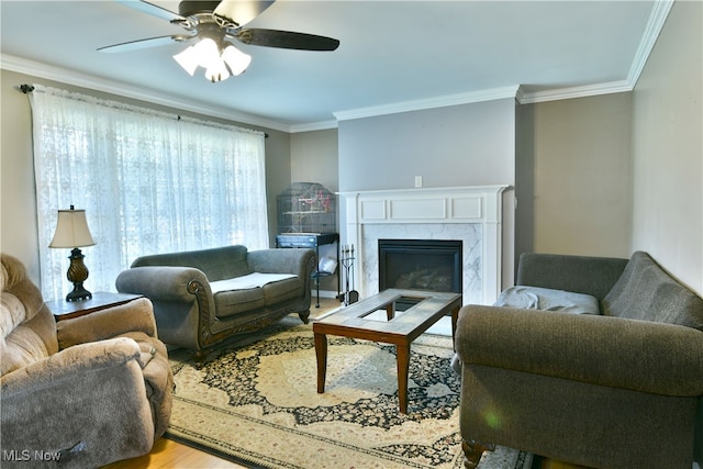 living room with crown molding, a premium fireplace, light hardwood / wood-style flooring, and ceiling fan