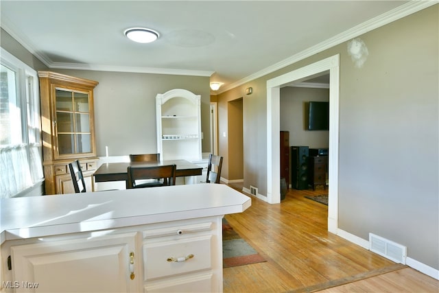 dining room with light hardwood / wood-style floors and crown molding