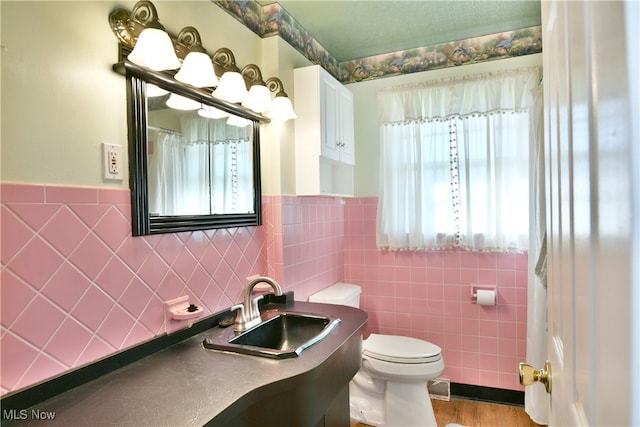 bathroom with tile walls, vanity, hardwood / wood-style floors, and toilet