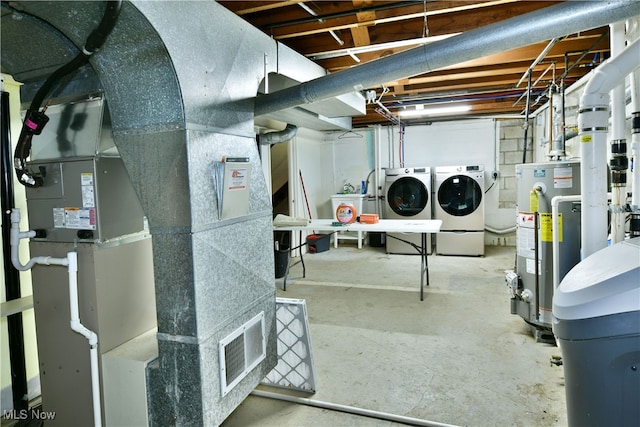 basement featuring washer and dryer, heating unit, and water heater