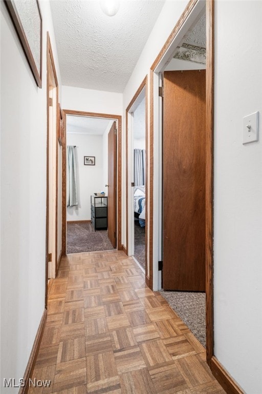 hall with a textured ceiling and light parquet flooring