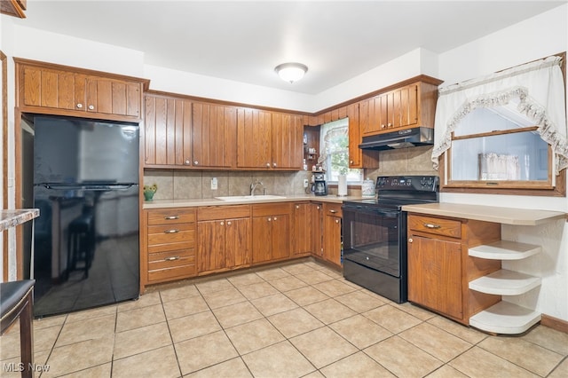 kitchen featuring backsplash, light tile patterned flooring, black appliances, and sink