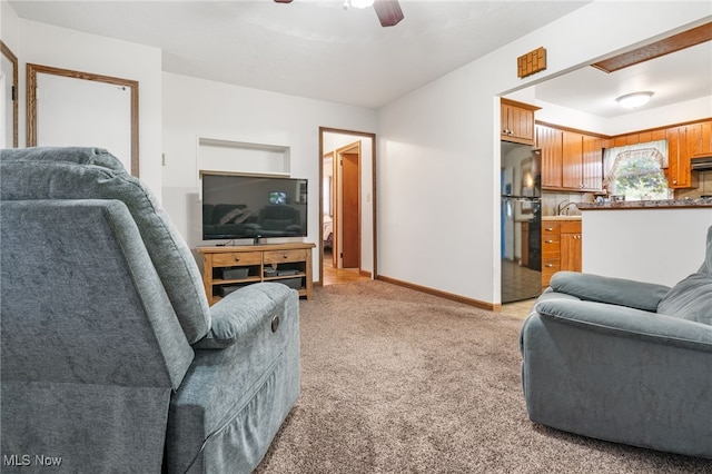 living room featuring sink, light carpet, and ceiling fan