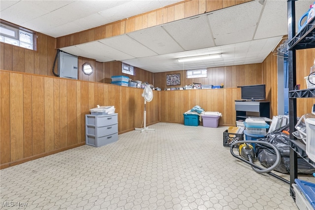 basement with a paneled ceiling and wooden walls