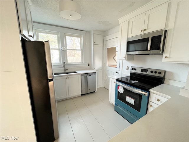 kitchen with white cabinets, stainless steel appliances, sink, and a textured ceiling