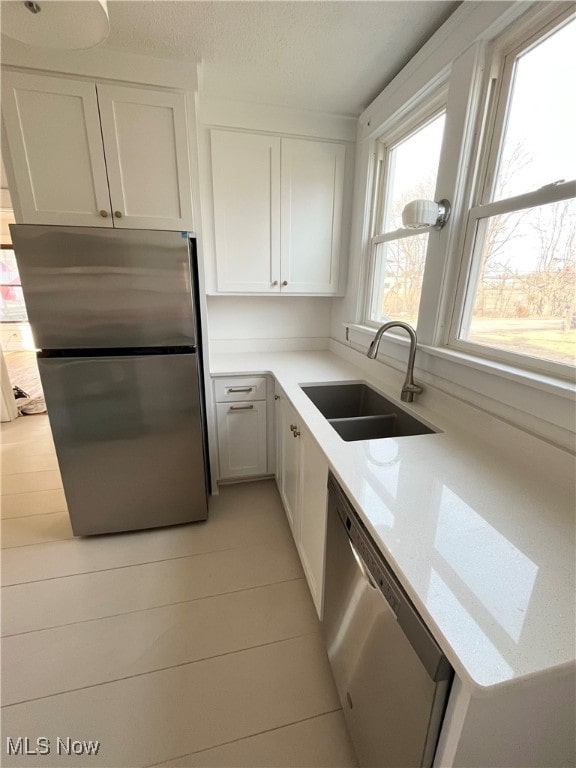 kitchen featuring white cabinetry, light stone countertops, appliances with stainless steel finishes, and sink