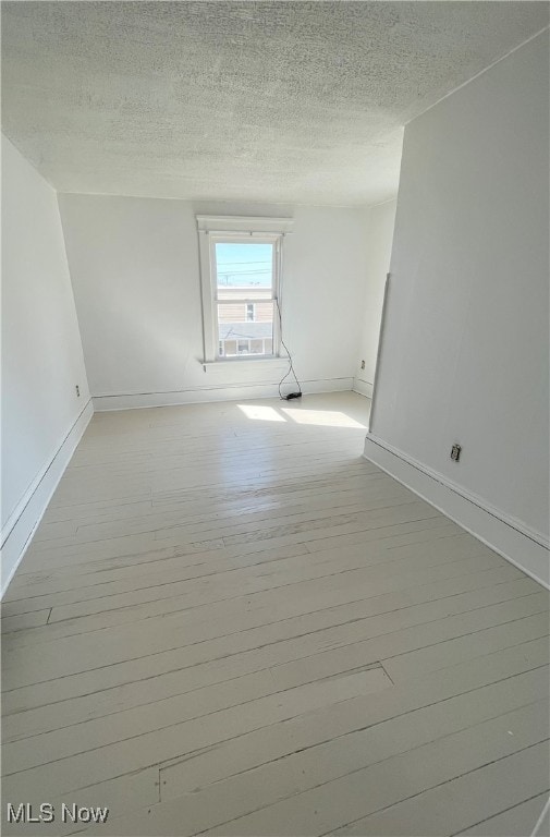 empty room with a textured ceiling and light hardwood / wood-style floors