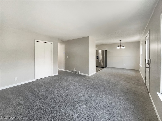 carpeted spare room featuring a chandelier