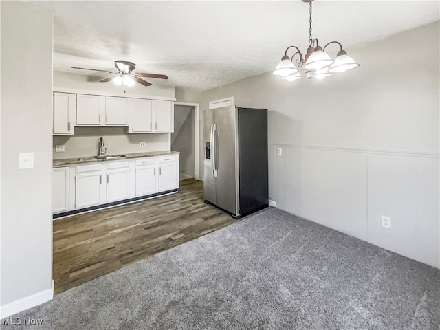 kitchen with hanging light fixtures, white cabinetry, dark wood-type flooring, stainless steel refrigerator with ice dispenser, and sink