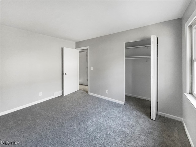 unfurnished bedroom with a closet and dark carpet