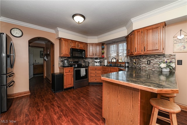 kitchen featuring dark wood-type flooring, crown molding, stainless steel appliances, and kitchen peninsula