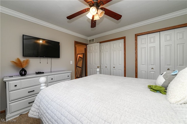 carpeted bedroom with crown molding, two closets, and ceiling fan