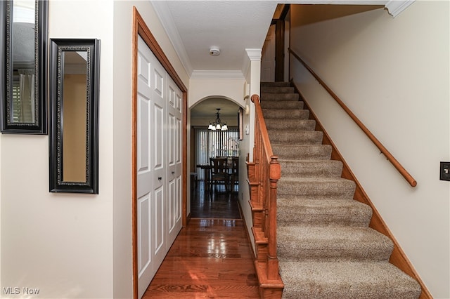 stairs featuring a notable chandelier, ornamental molding, wood-type flooring, and ornate columns