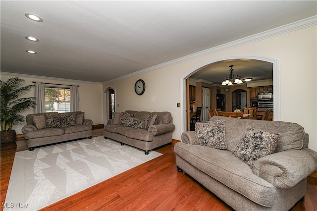 living room with ornamental molding, a notable chandelier, and hardwood / wood-style flooring