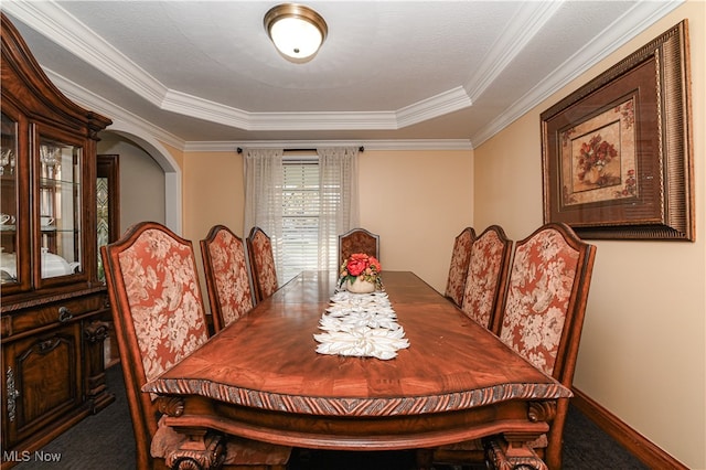 dining room with crown molding, a raised ceiling, and carpet