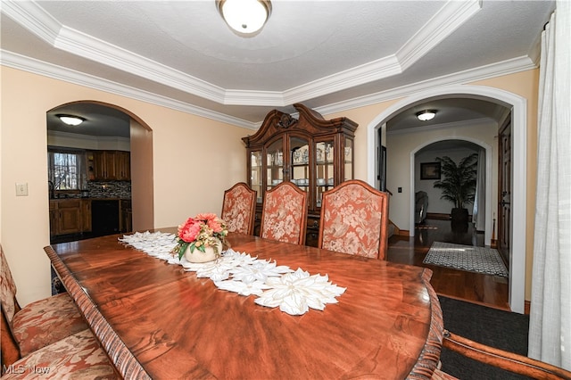 dining space featuring a tray ceiling, ornamental molding, a textured ceiling, and hardwood / wood-style floors