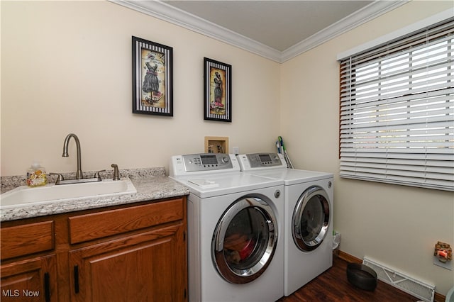 laundry room featuring cabinets, ornamental molding, dark wood-type flooring, sink, and washer and clothes dryer