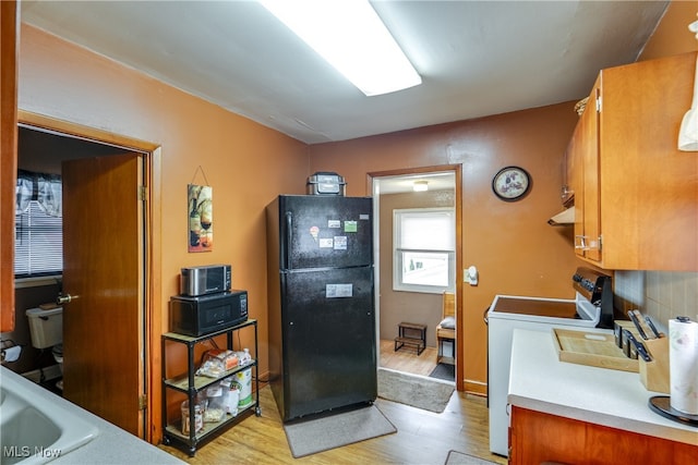 kitchen featuring light hardwood / wood-style flooring, black appliances, sink, and backsplash