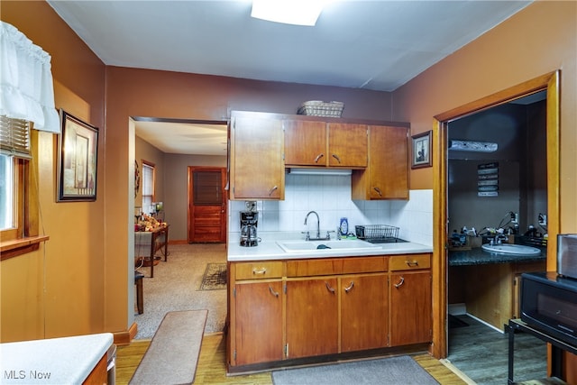 kitchen with decorative backsplash, sink, and light wood-type flooring