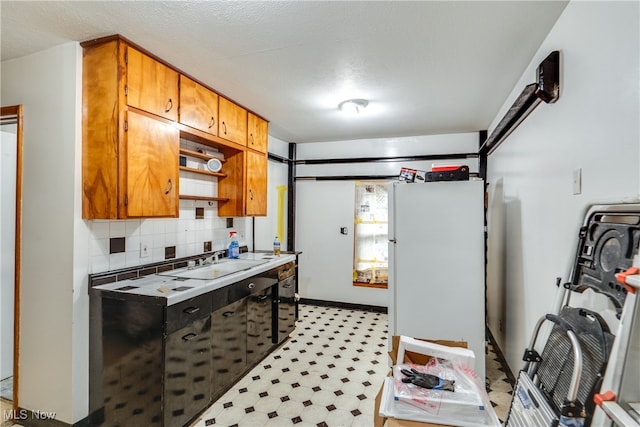 kitchen with a textured ceiling, decorative backsplash, sink, and white refrigerator