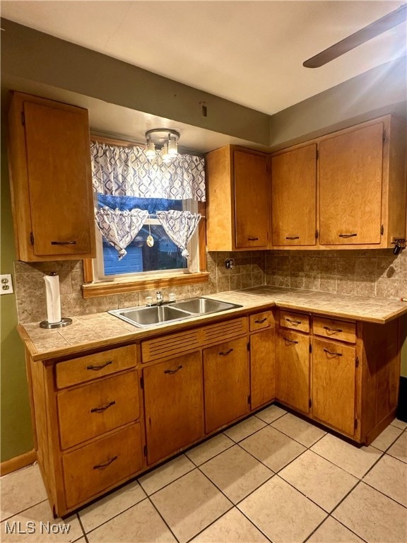 kitchen with decorative backsplash, sink, light tile patterned floors, and ceiling fan