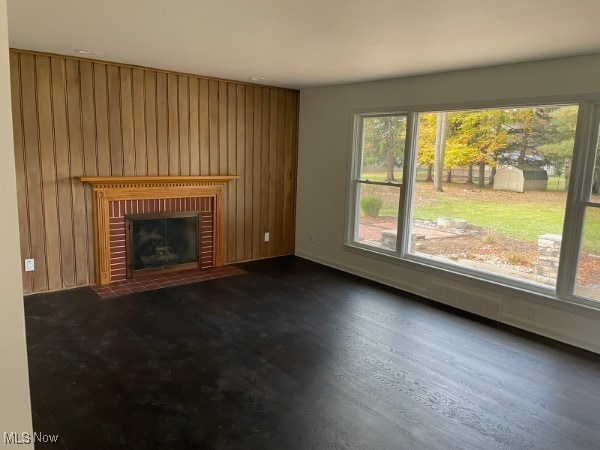 unfurnished living room featuring wooden walls, a fireplace, and dark hardwood / wood-style floors