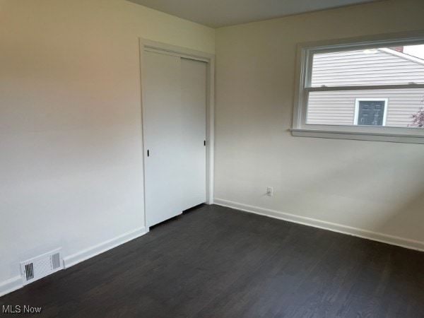 unfurnished bedroom featuring a closet and dark hardwood / wood-style flooring